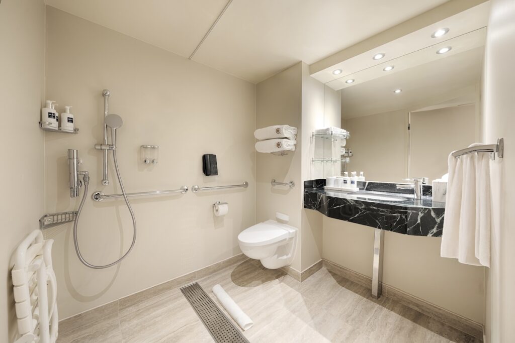 Roll-in shower with grab bars and accessible fixtures in an MSC Cruises accessible stateroom bathroom