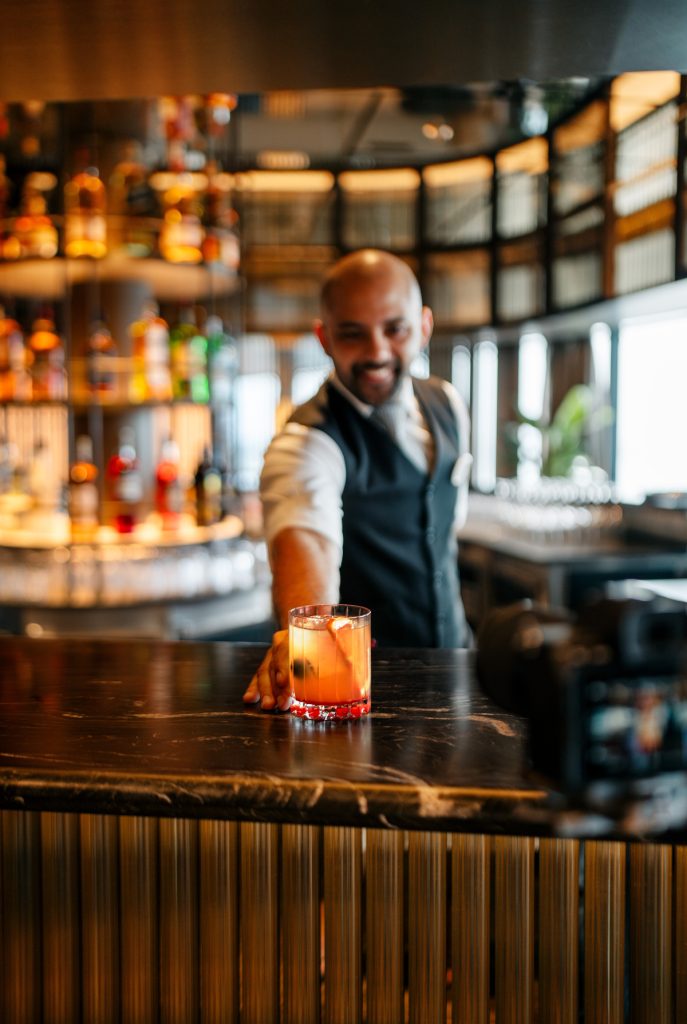 Norwegian Prima bars — bartender serving a cocktail at The Haven Bar