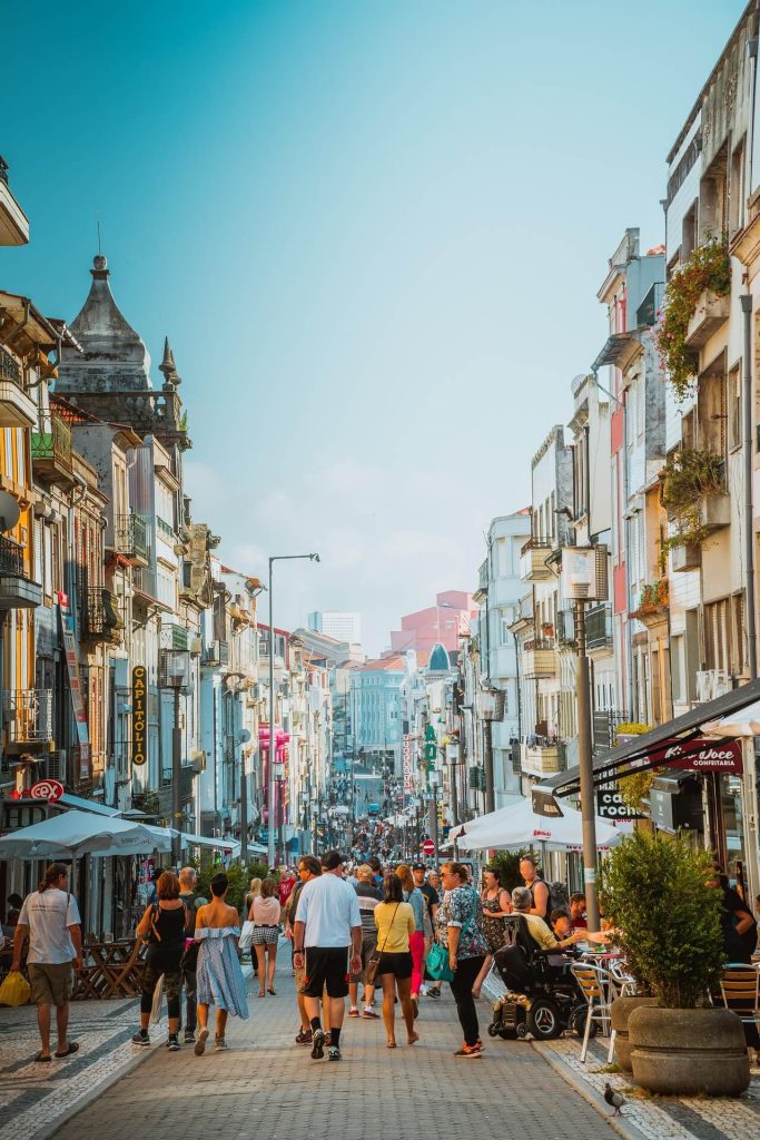 Tourists walking a busy port city street lined with shops and restaurants on a cruise port day
