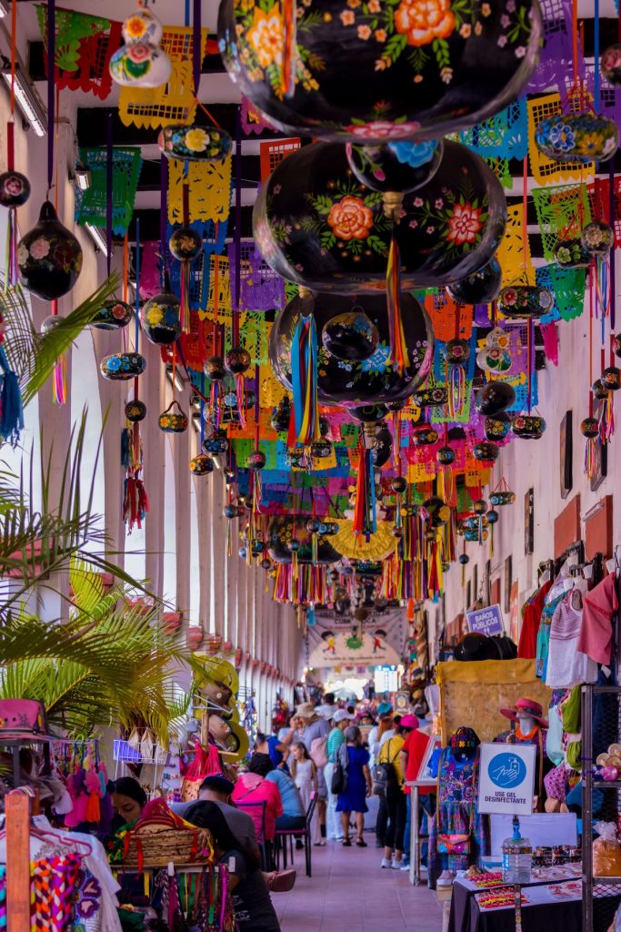 Busy indoor market in a Caribbean cruise with vendors and tourists browsing colorful stalls