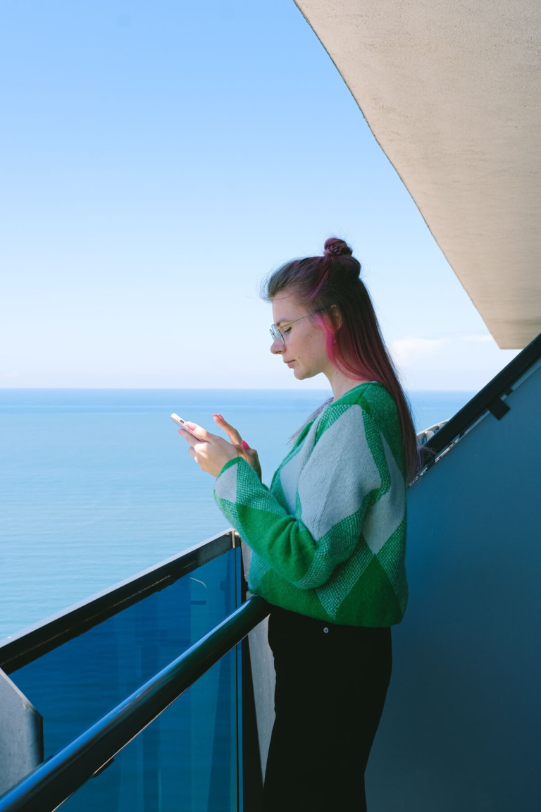 Traveler checking phone on cruise ship balcony, verification codes on a cruise with no cell service